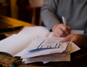 A man works on a pile of bills at a desk.