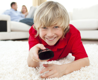 Boy holding a remote control watching TV