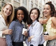 Four female coworkers smiling to camera outside